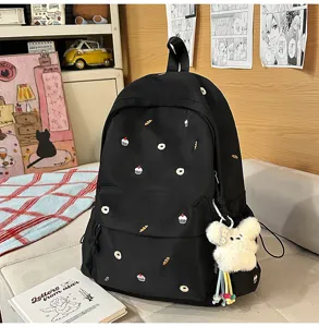 Black college style backpack detailed view showcasing cute pastry embroidery and plush bear pendant.