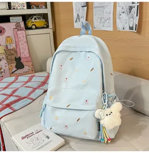 Detail view of the light blue college backpack featuring cute embroidery and a plush bear pendant.