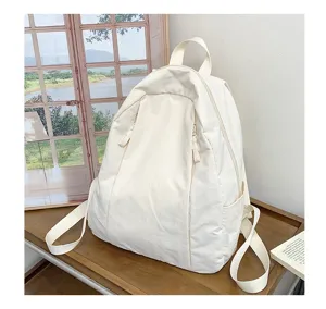 Close up view of minimalist white canvas backpack on wooden desk with scenic background display.