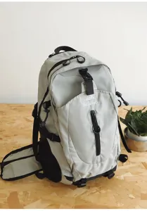 Grey outdoor backpack detail showing front zipper pocket, secure buckles and brand logo print.