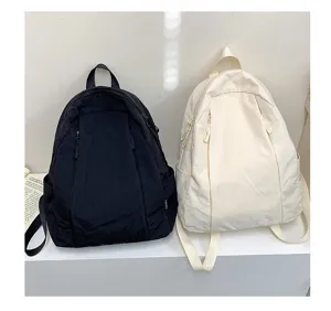 Detail view of casual solid color backpacks in black and beige, lightweight design for daily use.
