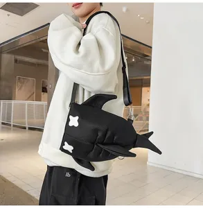 Detailed view of a trendy black shark shoulder bag featuring unique cross eyes and fin design.