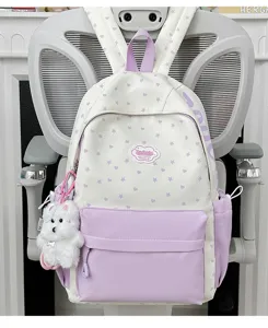 Close-up detail of sweet white backpack featuring purple star print and cute plush bear charm.