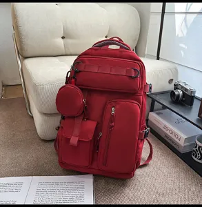 Detailed view of a multi-pocket red backpack in a cozy room setting with camera and books.