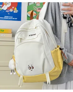 Large capacity color blocked school backpack for students with cute embroidery eyes and plush pendant.