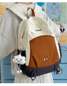 Large capacity color block school backpack with cute face embroidery and plush cloud pendant style.