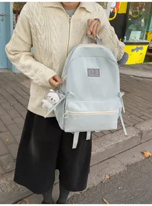 Gedetailleerd overzicht van de lichtblauwe casual rugzak met voorzak en pluche sleutelhanger.