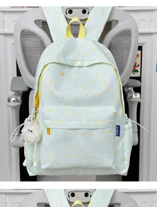 Detail view of cute light green backpack with yellow floral print, side pockets and plush charm.