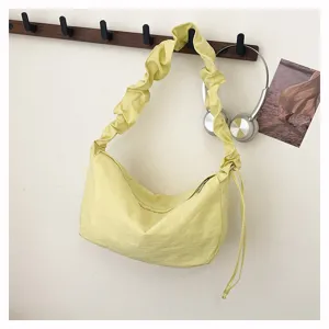 Detail view of the lightweight yellow nylon slouchy shoulder bag hanging on a minimalist hook.