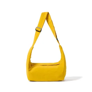 Detail view of a minimalist yellow shoulder bag with adjustable strap and zipper closure.
