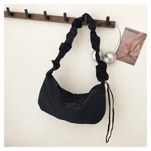 Black nylon slouchy dumpling shoulder bag hanging detail with pleated strap and side cords.