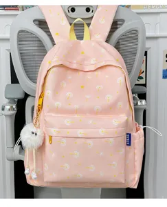 Detail view of the pink dandelion printed backpack featuring cute plush pendant and yellow zippers.