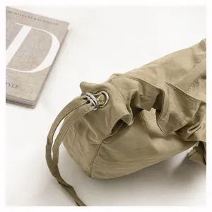 Nylon shoulder bag detail featuring pleated texture and metal drawstring hardware.