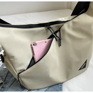 Close-up detail of the canvas messenger bag front pocket with zipper and brand patch.