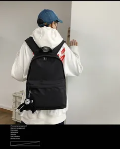 Detail view of black casual minimalist backpack with cute monkey plush pendant accessory.