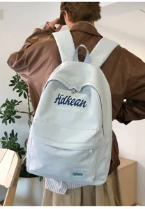 Casual light blue canvas backpack detail view, featuring front pocket and stylish printed lettering.