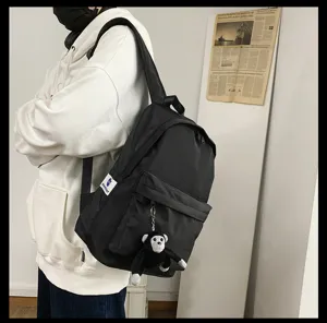 Classic minimalist black backpack with cute monkey keychain and spacious compartments for daily use.