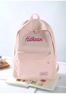 Detail shot of a pink campus style canvas backpack with front pocket and zipper closure.