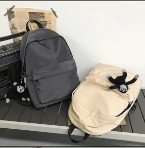 Minimalist nylon school backpack with cute plush monkey pendant for casual daily use.