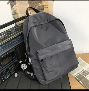 Minimalist grey casual backpack with cute plush monkey pendant, large capacity nylon daypack.