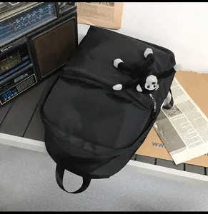 Classic black minimalist backpack with a cute plush monkey keychain for daily school use.