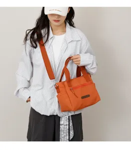 Details of the orange nylon casual tote bag with shoulder strap and front zip pocket for women.