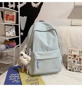 Detailansicht des niedlichen hellblauen Studentenrucksacks mit Sternmuster und Plueschbaer.