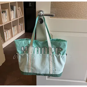 Dettaglio della borsa in tela verde con design bicolore e spallacci resistenti.