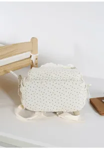 Close-up detail shot of a cute corduroy backpack featuring star print and delicate lace trim.