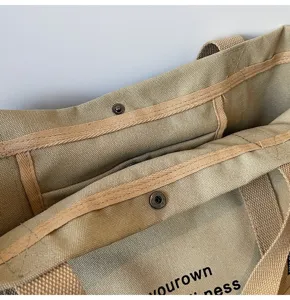 Canvas commuter tote bag detail showing durable fabric texture and secure snap button closure.