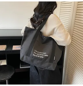 Detail view of a black canvas tote bag, casual large capacity shoulder bag for daily use.