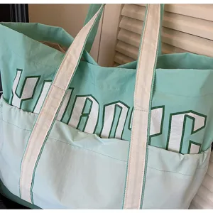 Grande borsa shopper in tela verde menta con tasca anteriore e stampa di lettere.
