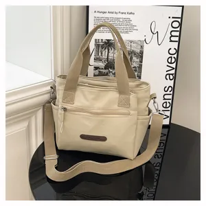 Casual khaki nylon shoulder bag with top handles, crossbody strap, and front zipper pocket.