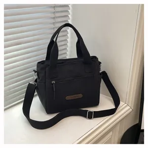 Casual nylon canvas shoulder bag for women, minimalist tote with strap and zipper pocket detail.