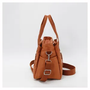 Side view detail of the orange nylon casual shoulder bag showing the adjustable strap and side pocket.