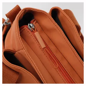 Detailed view of the orange nylon casual shoulder bag, showing the zipper and fabric texture.