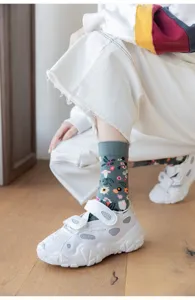 Detail shot of gray floral mid-tube cotton socks featuring cute plant and mushroom print.