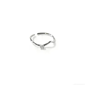 Primo piano dettagliato dell'anello ondulato minimalista argentato con zircone brillante.