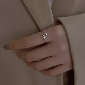 Detailed close-up shot of an adjustable silver dolphin fish tail ring, chic jewelry.