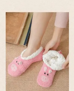 Nahaufnahme kuscheliger rosa Plüsch-Bodensocken mit Schweinchen-Design und weichem Futter.
