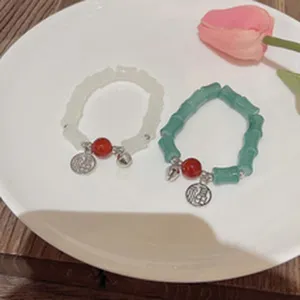 Elegant bamboo bead bracelet set with red bead and lucky charm, stylish wrist jewelry.