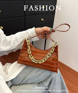 Details of brown crocodile pattern baguette handbag with stylish chunky gold chain strap.