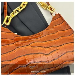 Crocodile pattern baguette bag detail shot, showcasing premium glossy brown texture and gold chain.