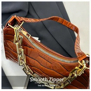 Brown crocodile pattern baguette bag detail showing smooth zipper and golden chunky chain.