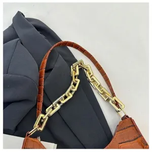 Detailed view of brown crocodile pattern underarm baguette bag with stylish gold chain strap.