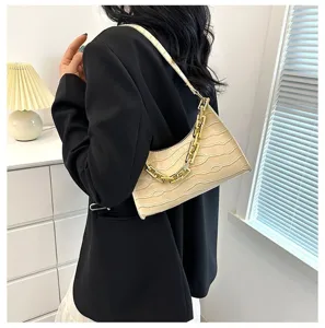Detailed shot of the beige crocodile pattern baguette bag showcasing the stylish gold chain.