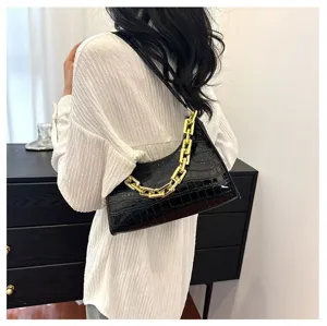 Detailed view of the black crocodile pattern baguette handbag featuring a chunky gold chain strap.