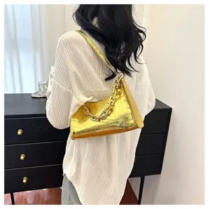Metallic gold crocodile pattern shoulder bag detail, stylish fashion accessory in indoor setting.