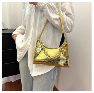 Close-up view of the metallic gold crocodile embossed baguette bag worn by model, stylish.