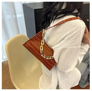 Detailed view of brown crocodile embossed leather baguette bag with chic chunky gold chain strap.